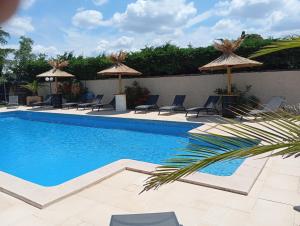 a swimming pool with chairs and umbrellas at Logis Hôtel Acotel Avignon Nord in Le Pontet