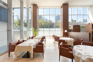 ein Restaurant mit Tischen und Stühlen und großen Fenstern in der Unterkunft Oriental Hotel Hiroshima in Hiroshima