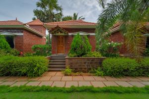 a red brick house with a wooden door at Nathan Resort with Swimming Pool in Puducherry