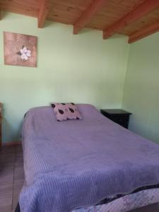 Cama en habitación con manta morada en Cabaña del Lago, en San Carlos de Bariloche