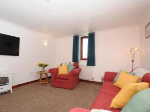 a living room with two red chairs and a tv at West Lee in Bude