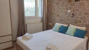 a white bed with blue pillows and a brick wall at Gea luxury apartment Myrina 2 in Myrina
