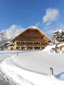 ein großes Holzgebäude im Schnee mit einem Pfad in der Unterkunft Paulbauer in St. Wolfgang