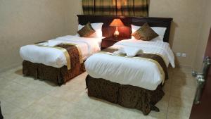 a hotel room with two beds and a lamp at ضيافة بيت المسرة للشقق المخدومة in Al Khobar