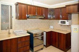a small kitchen with wooden cabinets and a sink at ضيافة بيت المسرة للشقق المخدومة in Al Khobar