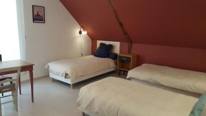 a room with two beds and a table and a desk at La grange des Thermes in Beaucens