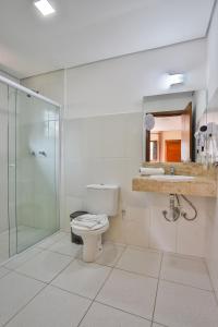 a bathroom with a toilet and a glass shower at Villaggio di Roma - Campos do Jordão in Campos do Jordão
