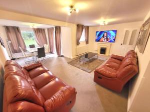 a living room with a brown leather couch and a tv at Stunning! 3 Bed Entire House with Free Parking in Stapleford