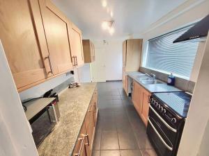 a kitchen with wooden cabinets and a black stove at Stunning! 3 Bed Entire House with Free Parking in Stapleford