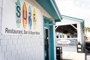 a building with a sign for a restaurant with surfboards at The Surf Beach Motel in Amelia Island