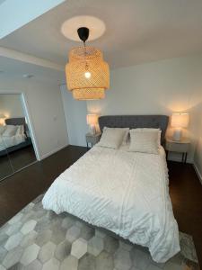 1 dormitorio con cama blanca y lámpara de araña en Cozy and modern Pemberton Heights Suite, en North Vancouver