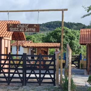 a gate with a sign in front of a restaurant at Chalé Raiz da Serra in Gravatá