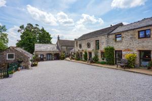an empty driveway in front of a stone house at Bolehill Farm Cottages in Bakewell