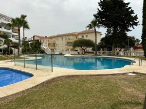 a swimming pool in a yard with a building in the background at Kandy Apartment in Mijas Costa