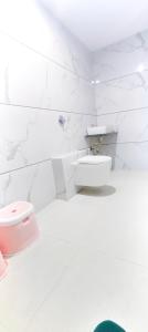 a bathroom with a toilet and a white wall at Hotel Yog Palace Newly Renovated in Shirdi