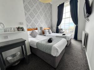 韦茅斯The Jubilee Hotel West- with Spa Facilities & Smokehouse - NEWLY REFURBISHED FACILITIES的有两张床和一扇窗户的酒店房间
