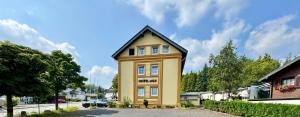 a yellow house with a black roof at Hotel Moji 3 Landhaus Köln in Lindlar
