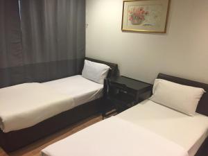 two beds in a room with white sheets at Hotel Conforto in Singapore