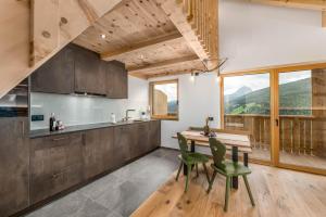kuchnia z drewnianym stołem i zielonymi krzesłami w obiekcie La Munt agriturism w mieście San Vigilio di Marebbe