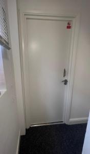une porte blanche dans une pièce avec de la moquette noire dans l'établissement Cosy Self contained Studio flat, à Londres