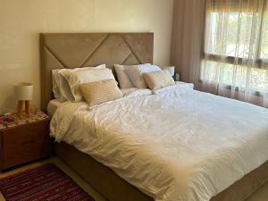 a bedroom with a large bed with white sheets and pillows at Appartement haut standing près de la Plage in Skhirat +7 photos