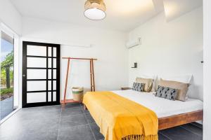 a bedroom with a bed with a yellow blanket on it at T3 Moderne avec piscine Oasis de nature et Sérénité in Petit-Canal