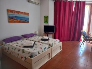 a bedroom with a bed and a tv and red curtains at Appartamento t0 n 7 situato complesso turistico porto antico 2 in Santa Maria