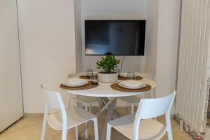 a white dining room table with chairs and a tv at La Grotta 250m dal lago RDA Lux AP in Mendrisio