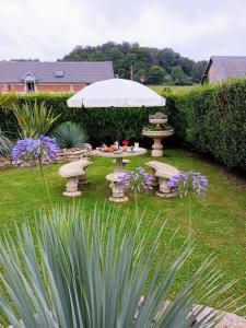 a picnic table with an umbrella in a garden at L' Har & Lam in Leuilly-sous-Coucy