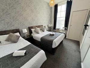 韦茅斯The Jubilee Hotel West- with Spa Facilities & Smokehouse - NEWLY REFURBISHED FACILITIES的酒店客房设有两张床和吊灯。