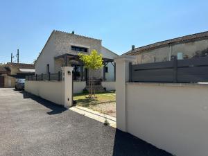 ein Haus mit einem weißen Zaun und einer Auffahrt in der Unterkunft Maison Isle sur la sorgue in LʼIsle-sur-la-Sorgue
