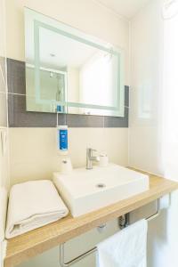 a bathroom with a white sink and a mirror at Brit Hotel Confort Manosque Cadarache in Manosque +93 photos