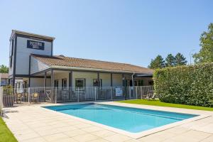 a swimming pool in front of a house at Brit Hotel Confort Manosque Cadarache in Manosque