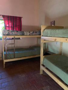 a room with three bunk beds and a window at Gran Casa Hostel y Camping in Tilcara