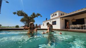 two children are swimming in a swimming pool at Masos Bruguera - Finca Llambrich in Deltebre