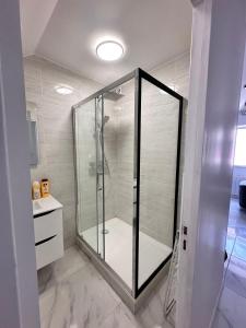 a shower with a glass door in a bathroom at Appartement Calme Moderne proche de disneyland WIFI & Café gratuit & Arrivée Autonome in Bussy-Saint-Georges
