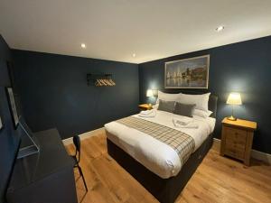 a bedroom with a large bed with a blue wall at The Six Bells in Bourne