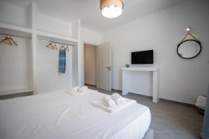 a white bedroom with a large white bed and a tv at Grey Comfort in Glinado Naxos