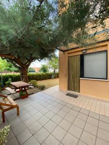 a patio with a picnic table and a tree at Appartamento al mare - Marotta in Marotta