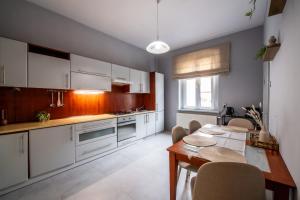 a kitchen with white cabinets and a table with chairs at Pokoje nad Kłodnicą in Gliwice