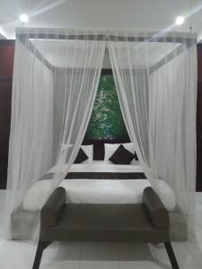 ein Schlafzimmer mit Himmelbett und Fenster in der Unterkunft Villa Pool Private and Romantic In Kuta Bali in Kuta