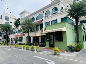 a green and white building with palm trees on a street at New Ekamai Thonglor Luxury Home near 711, BTS, Mall in Khlong Toei