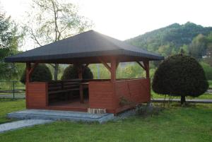 a wooden gazebo with a bench in a park at Pod Żurawiem in Bóbrka