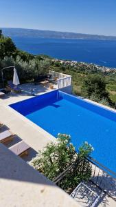 a blue swimming pool with a view of the ocean at Villa Conte in Podstrana