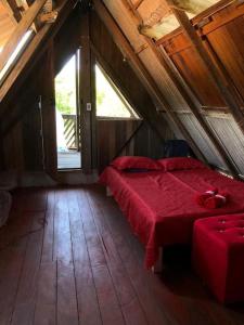 a bedroom with a red bed in a attic at Chalé Maison Blanche in Maracanã