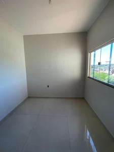 an empty room with a window and a white wall at Casa 3 quartos 6 pessoas garagem in Coração de Jesus