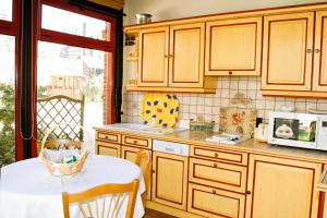 a kitchen with wooden cabinets and a table with a microwave at La Villa Bligny in Étretat