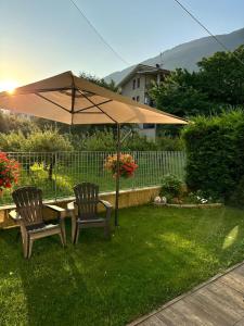 two chairs and a table with an umbrella in a yard at Casa Lina Tirano in Tirano