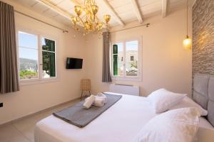 a bedroom with a large white bed with a chandelier at ARCHONTIKO 1922 in Argostoli +18 photos