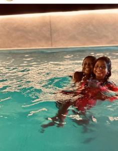 two young girls are smiling in a swimming pool at Luxury Paiva Flat in Recife